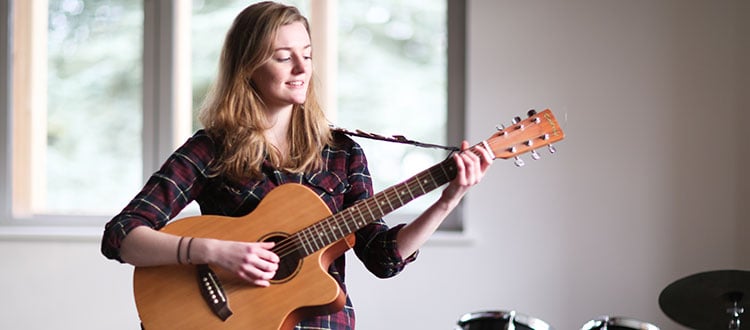 Student playing a guitar in the rock and popular music department