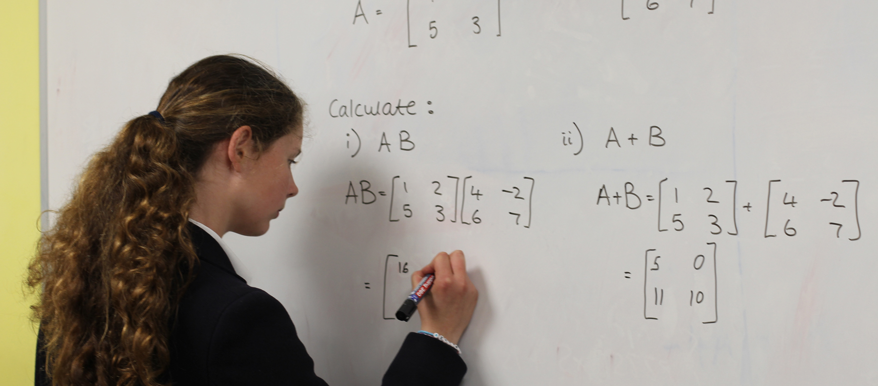 Girl working on a maths problem at the whiteboard at our Specialist Maths School in Wells Somerset