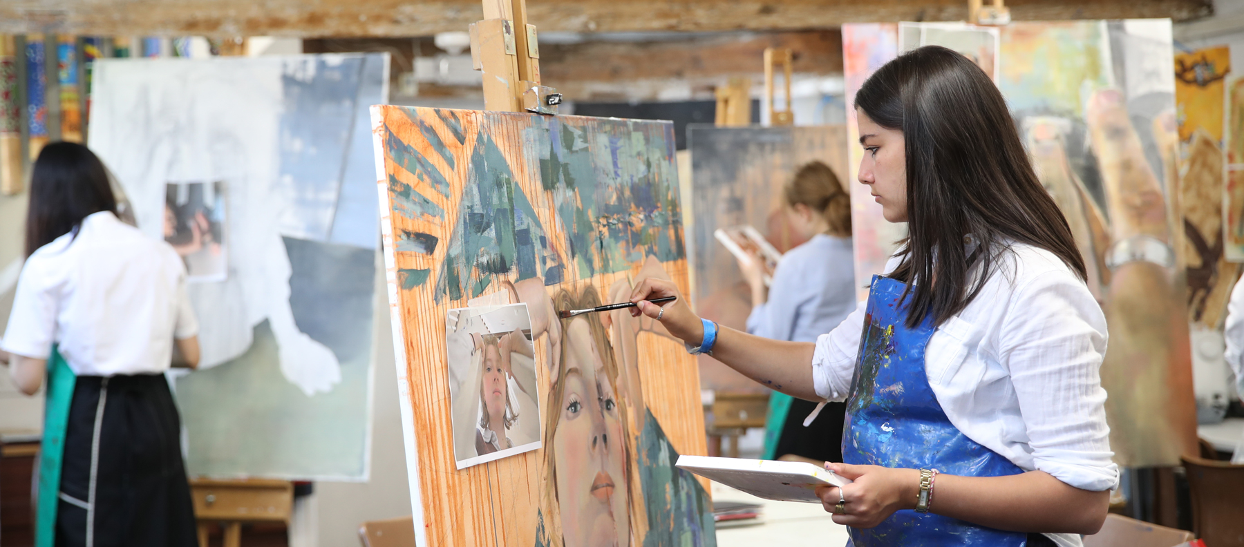 Girl painting at an easel at our Independent School in Somerset