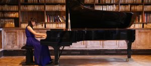 Girl in evening dress playing Steinway Piano in Quilter Hall at our Specialist Music School in England
