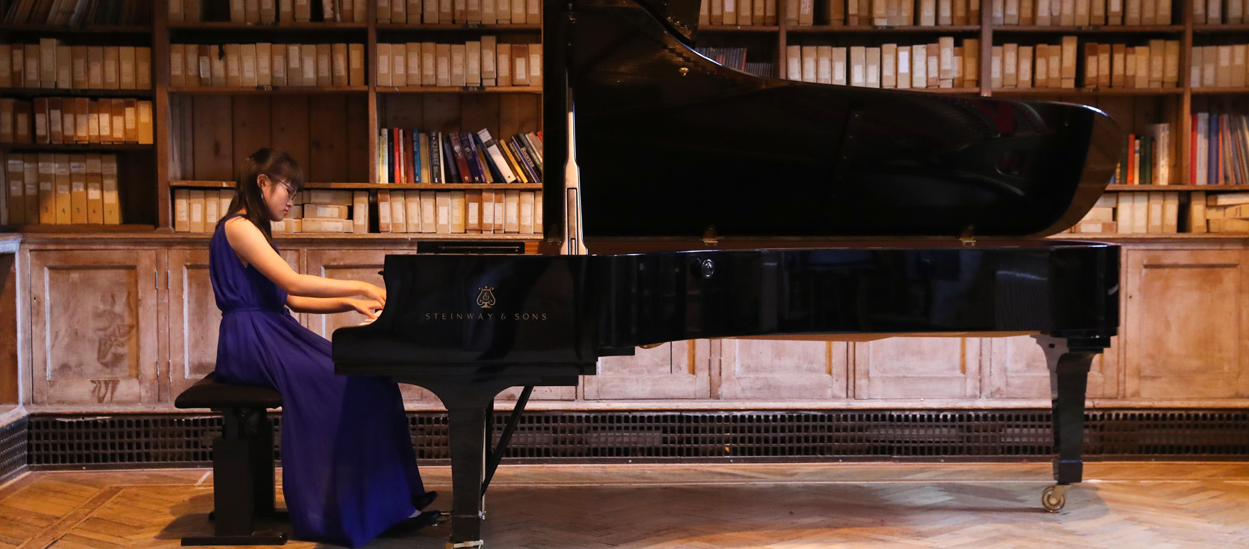 Girl in evening dress playing Steinway Piano in Quilter Hall at our Specialist Music School in England