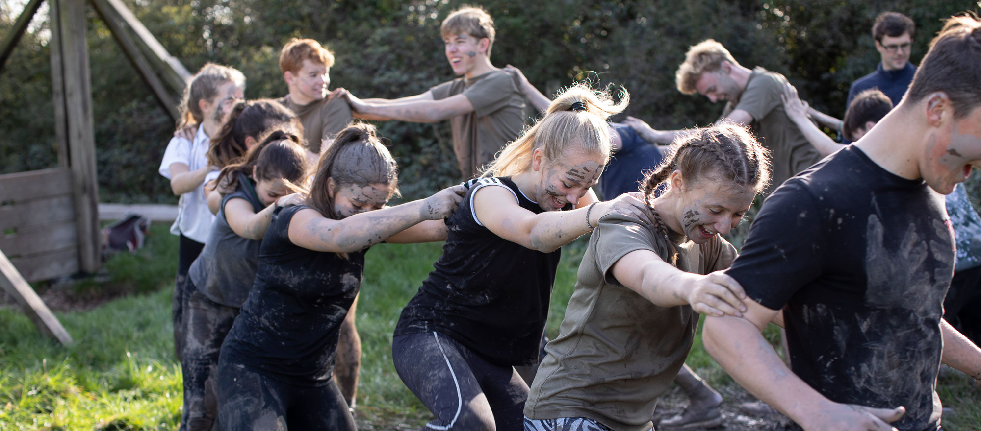 Group of muddy pupils doing a teamwork exercise as part of their outdoor education at our independent school in Somerset