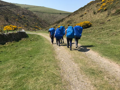 A group of pupils with big blue backpacks setting off on an expedition