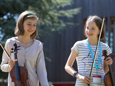 Two girls walking with violins at our Specialist Music School in England