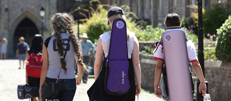 Group of pupils walking in Wells carrying strings cases