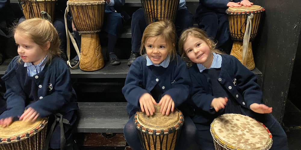 Girls in Wells Pre-Prep playing on African drums