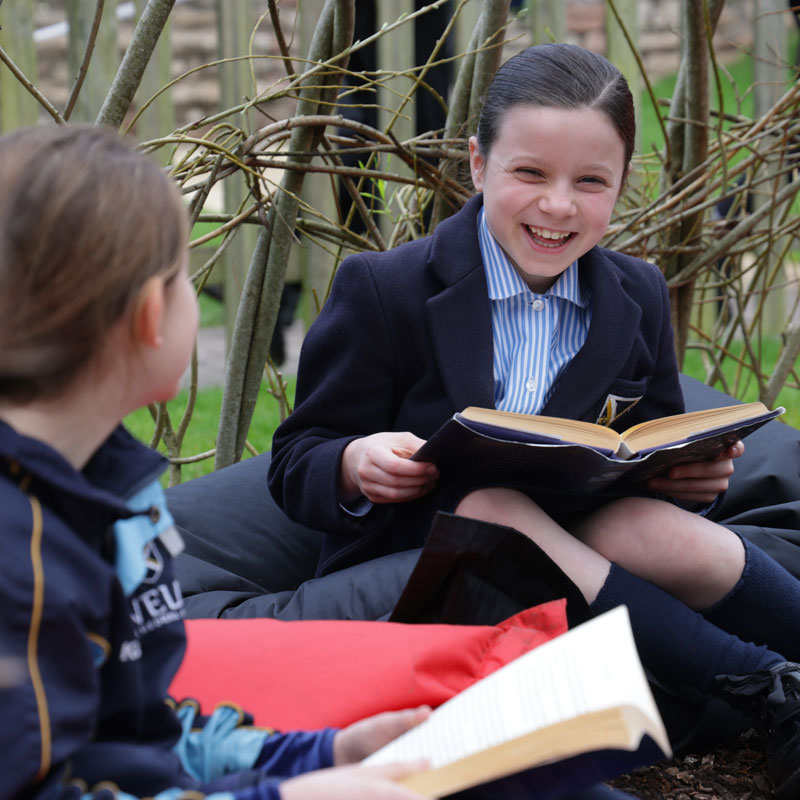Two Prep School girls reading in the willow den at our independent prep school in Wells, Somerset